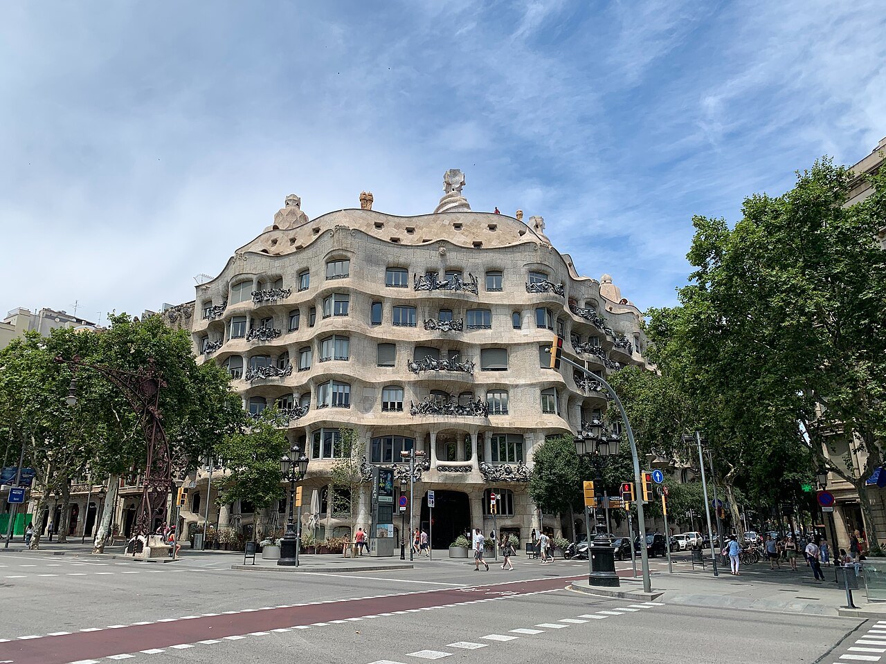 Casa Milà's wave-like stone façade across the Passeig de Gràcia, with plane trees on both sides.